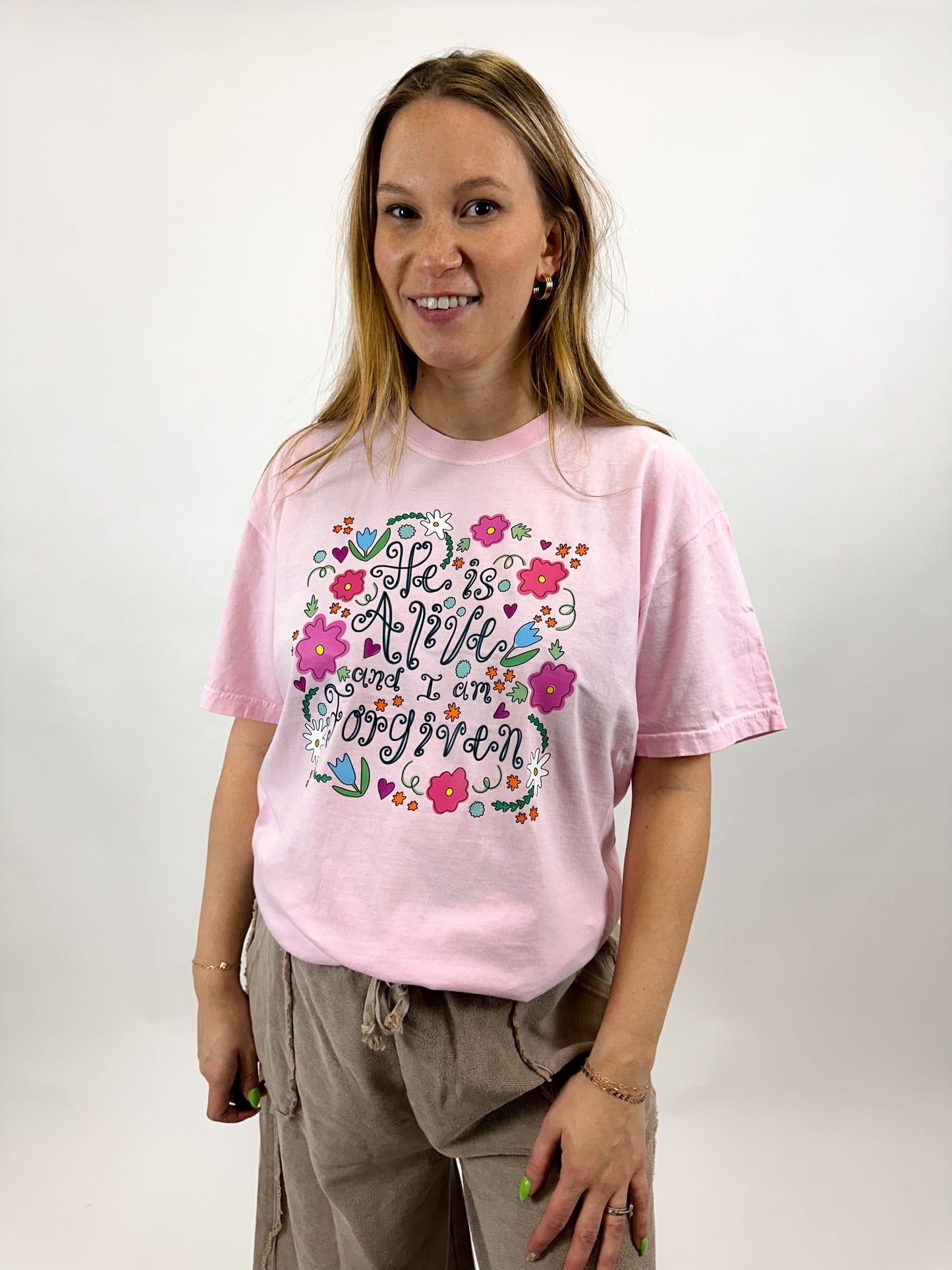 "He is alive and I am forgiven" Easter graphic with hand drawn floral design on a light pink tee. This Oak and Willow x K.Box Designs graphic tee is perfect for the Easter season.