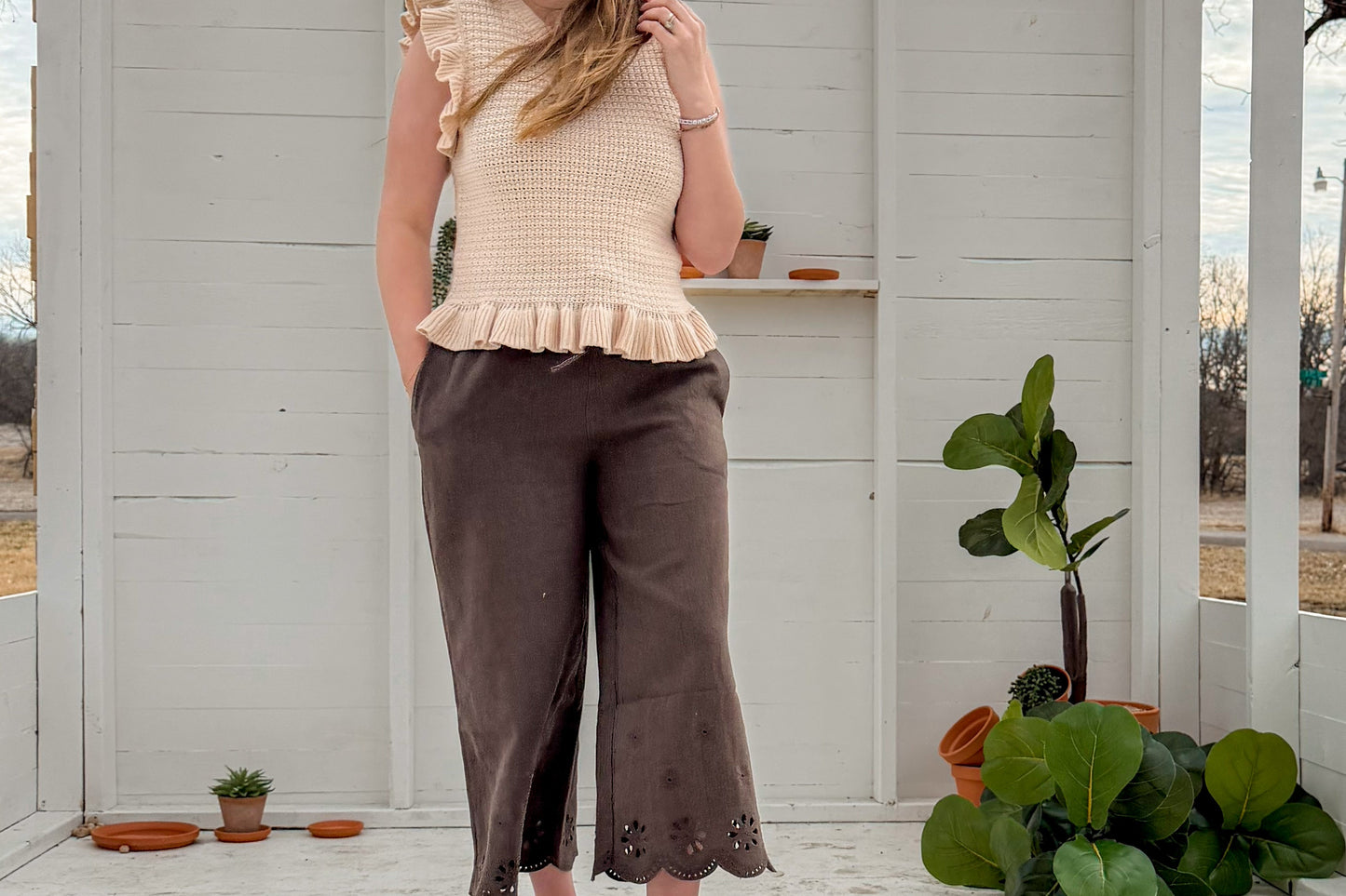 Woman standing in front of a white wooden structure with plants around